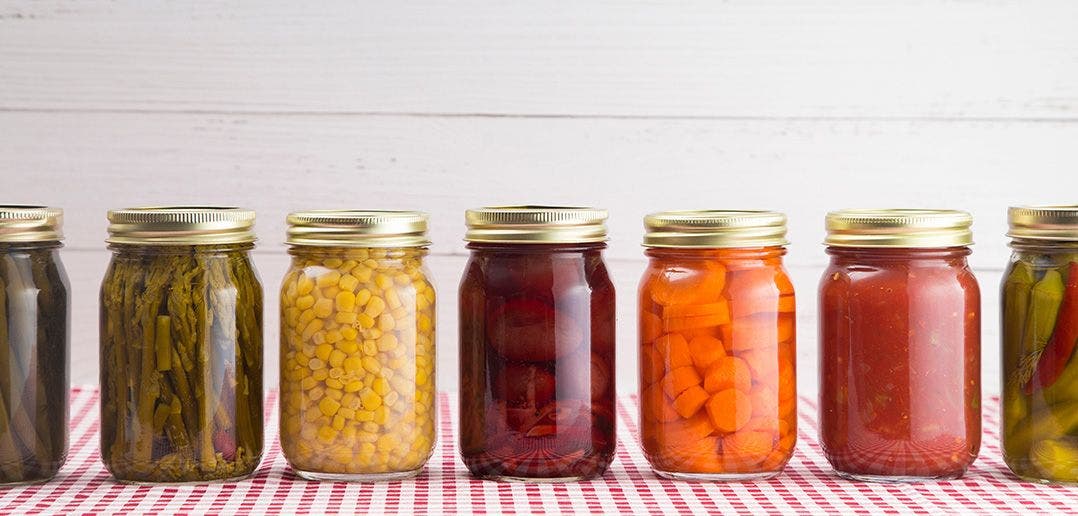 multiple glass jars of vegetables pickles and jams