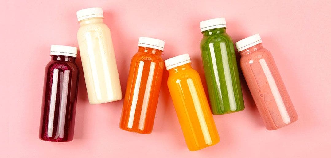 Bottles of Juice laid out on a pink background