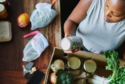 A woman looking at produce and jars in a box