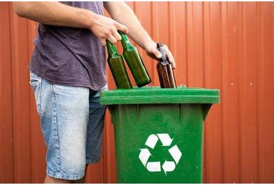 A person recycling glass bottles