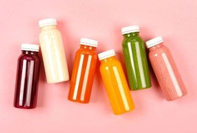 Six bottles of Juice laid out on a pink background