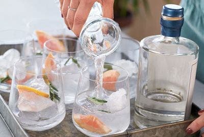 Mocktails being poured onto a tray of 4 glasses